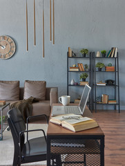 Wooden desk working and studying table, close up, computer book and grey room background, sofa and bookshelf style, clock and gold lamp.