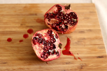 Pomegranate cut in half on a wooden cutting board. Selective focus.
