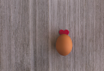 One Organic Brown Chicken egg  Decorated  Red Heart like Ears on a Wooden Table. Copy Space. Easter Concept.