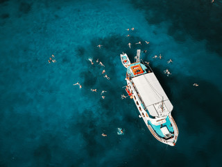 Aerial shot of beautiful blue lagoon at hot summer day with sailing boat. Top view of people...