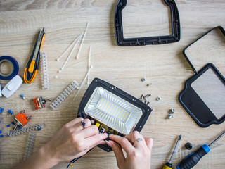 The girl performs male work   (repairs a diode lamp)