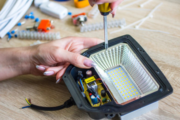 The girl performs male work   (repairs a diode lamp)