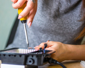 The girl performs male work   (repairs a diode lamp)