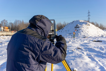 Surveyor in the winter on the construction site conducts topographic and cadastral work