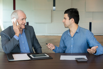 Senior and young business partners having negotiation. Coworkers discussing deals and sharing ideas on phone. Negotiation concept