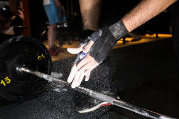 male powerlifter hand in talc and sports wristbands preparing to bench press.