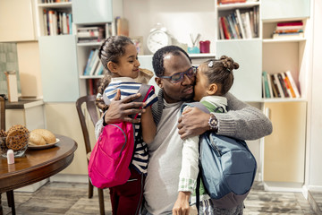 Loving caring father hugging his cute little girls going to school