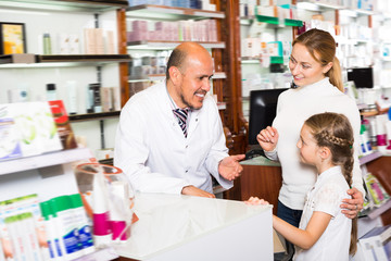 Smiling adult male pharmacist helping customers