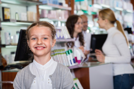 Little glad girl  in the pharmacy with parents and pharmacist