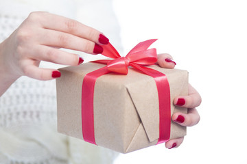 girl holding a present in hands, woman opening the box wrapped in craft paper on white isolated background, concept winter holiday
