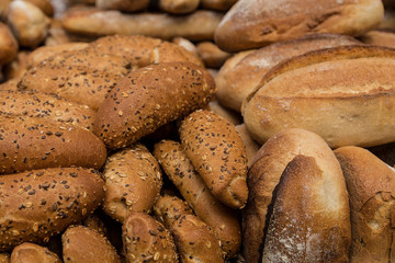 Background of loaves of fresh white bread with sesame seeds and grains close-up on the shelf in the market