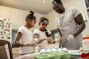 Two girls feeling excited while beating eggs for cooking pie