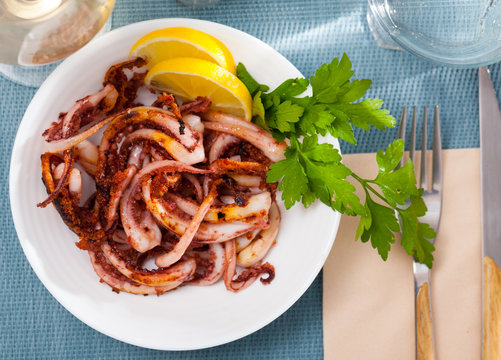 Delicious cooked squid or octopus tentacles with lemon and parsley on a plate