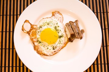 Tasty and freshly cooked eggs seasoned with dried dill laid out on a white plate. With yashnitsa rye crackers are.