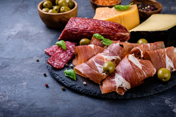 meat plate,  prosciutto and cheese, salami,  sausage and olives on gray  background