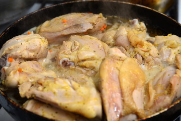 Fried chicken in a pan in oil with spices.