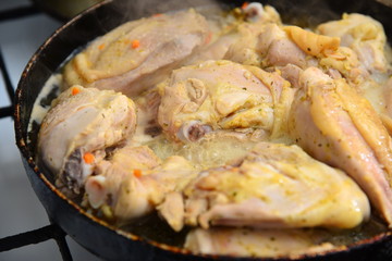 Fried chicken in a pan in oil with spices.