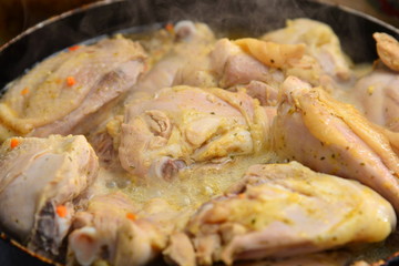 Fried chicken in a pan in oil with spices.