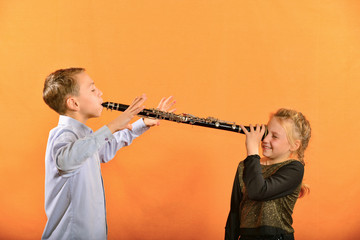 The boy plays the clarinet in the girl’s ear, the outraged girl waves her arms.