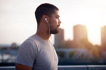 Close up image of fit young sportsman wearing earphones focusing for his training.
