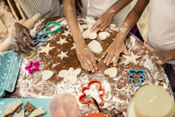 Little helpful daughters joining their father while making cookies