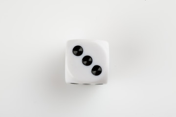 Single white with black dots dice on a white background, showing number three