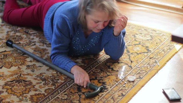 Sick elderly woman lying on the floor and suffering from pain