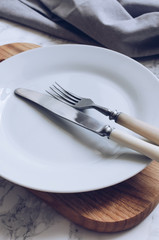 Fork, knife and plate on wooden board