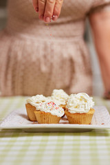 Sprinkling with confectionery small Easter cakes on the table in the cozy light kitchen
