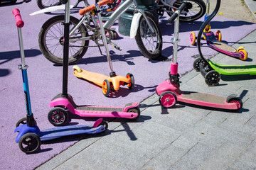 Spring and summer activities - many kick scooters and bicycles in park at children's playground