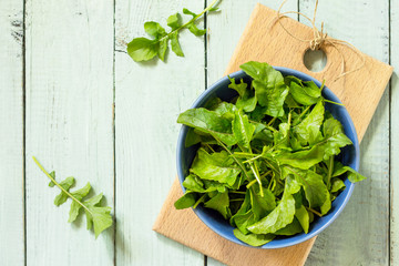 Fresh salad arugula leaves on rustic a kitchen wooden table. Top view flat lay background. Copy space.