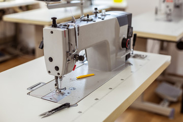 Big sewing machine being used in a process of manufacturing of new dresses