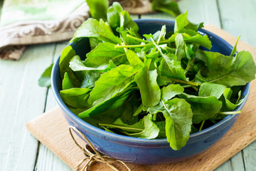 Fresh salad arugula leaves on rustic a kitchen wooden table.