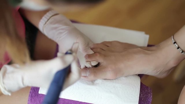 Experienced master makes hardware pedicure to woman in beauty salon.