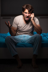 Fototapeta premium Young man talking on phone in bed