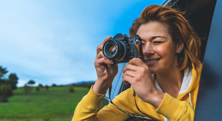 smile tourist girl in an open window of a auto car taking photography click on retro vintage photo camera, photographer looking on camera technology, blogger using hobby content concept, enjoy trip