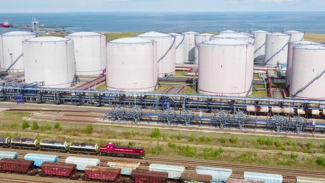 A freight train is moving by the oil refinery on the seashore