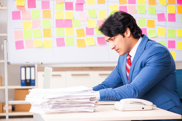 Young handsome employee with many conflicting priorities 