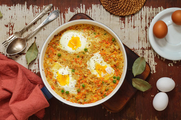 Wheat porridge with vegetables and eggs in a white pan