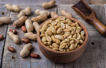 Peanuts in small wooden bowl on natural rustic desk.