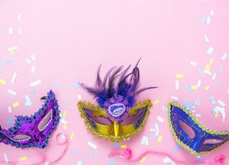 Obraz premium Table top view aerial image of beautiful colorful carnival festival background.Flat lay accessory object the several mask & decor confetti on modern pink paper at home office desk studio.copy space.