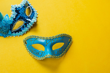 Table top view aerial image of beautiful colorful carnival season or photo booth prop Mardi Gras background.Flat lay object blue mask on modern yellow wallpaper.Free space for creative design mock