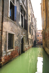 View on the historic architecture and the canal between the ancient buildings in Venice, Italy on a sunny day.