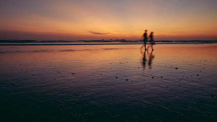 two people walking on beach