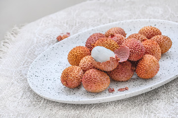 Fresh organic lychee fruit in a bowl on a rustic wooden background. Healthy vegan food concept. Close-up