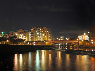 the river aire in leeds at night showing buildings on both sides of crown point bridge and the weir with bright lights reflected in the water