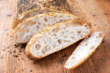 Traditional Italian ciabatta bread with herbs as closeup on a cutting board