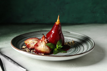 Plate with sweet pears stewed in red wine on table