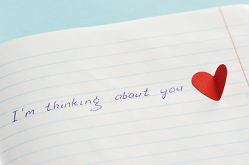 Text: I think about you. The text is written on a piece of paper. Close-up. View from above.