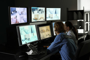 Security guards monitoring modern CCTV cameras in surveillance room
